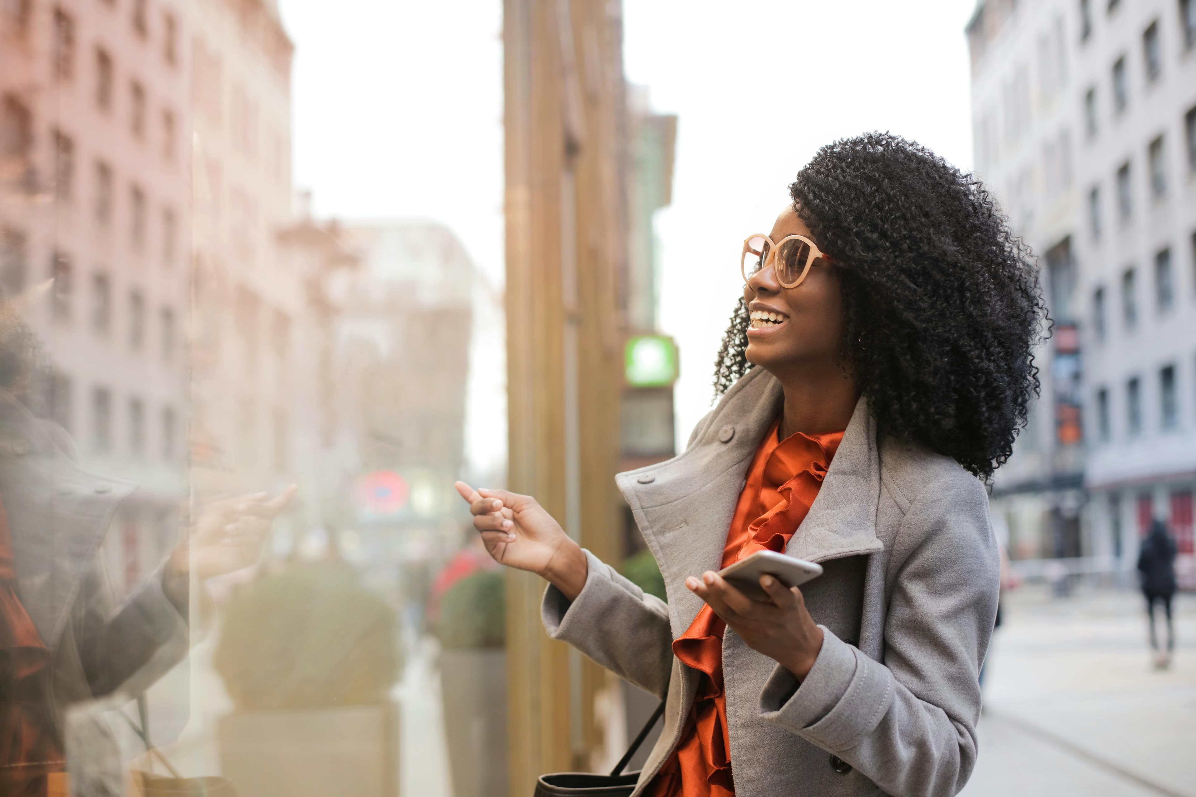 woman wearing glasses window shopping with a phone in her hand