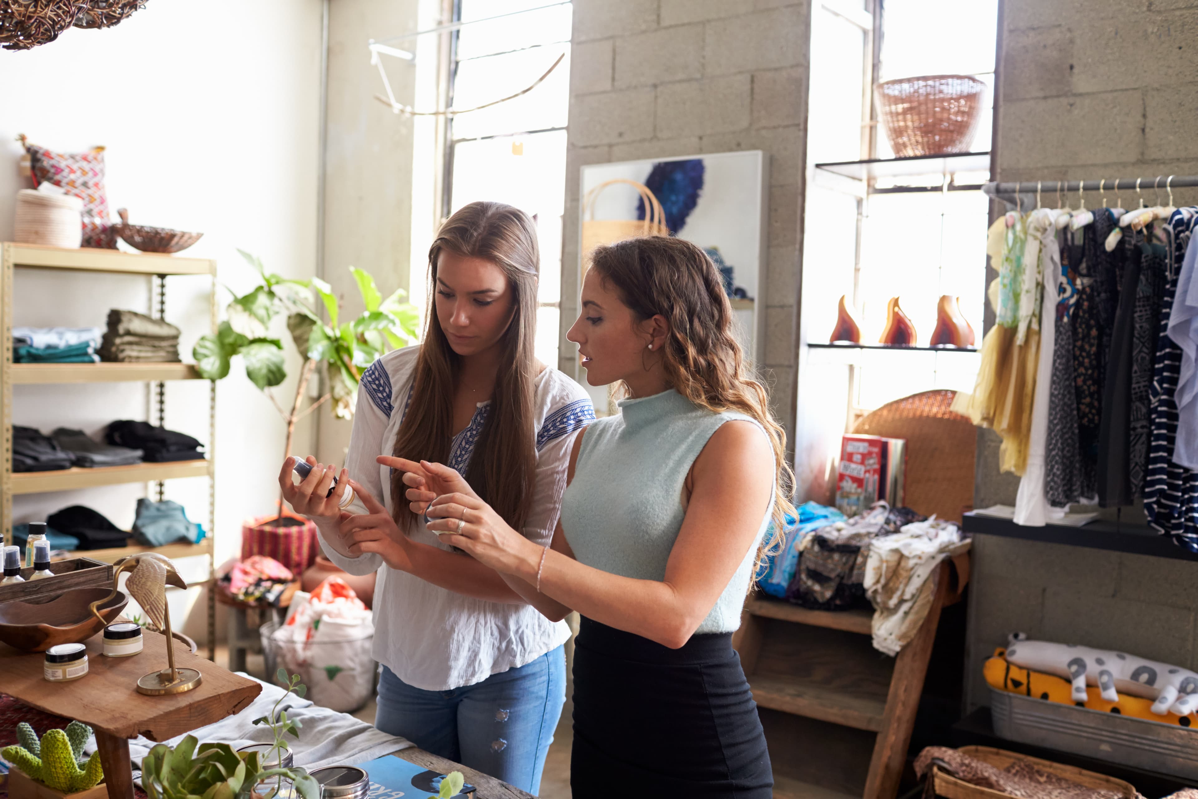 female store associate chatting with female client as she displays a product