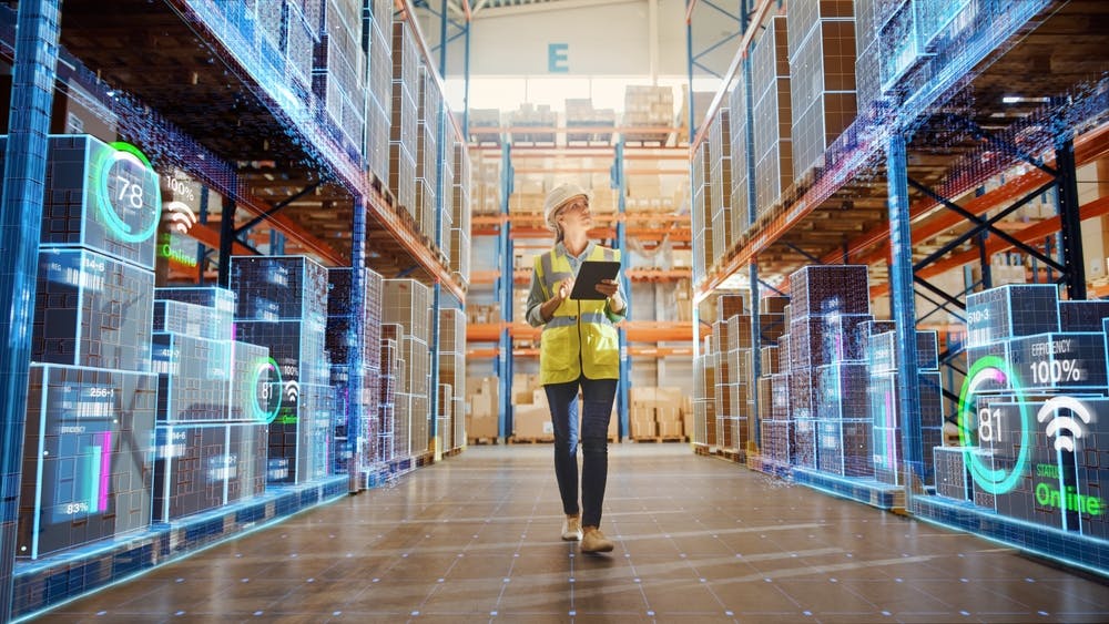 female warehouse worker walking through tech-enabled retail warehouse with ipad 