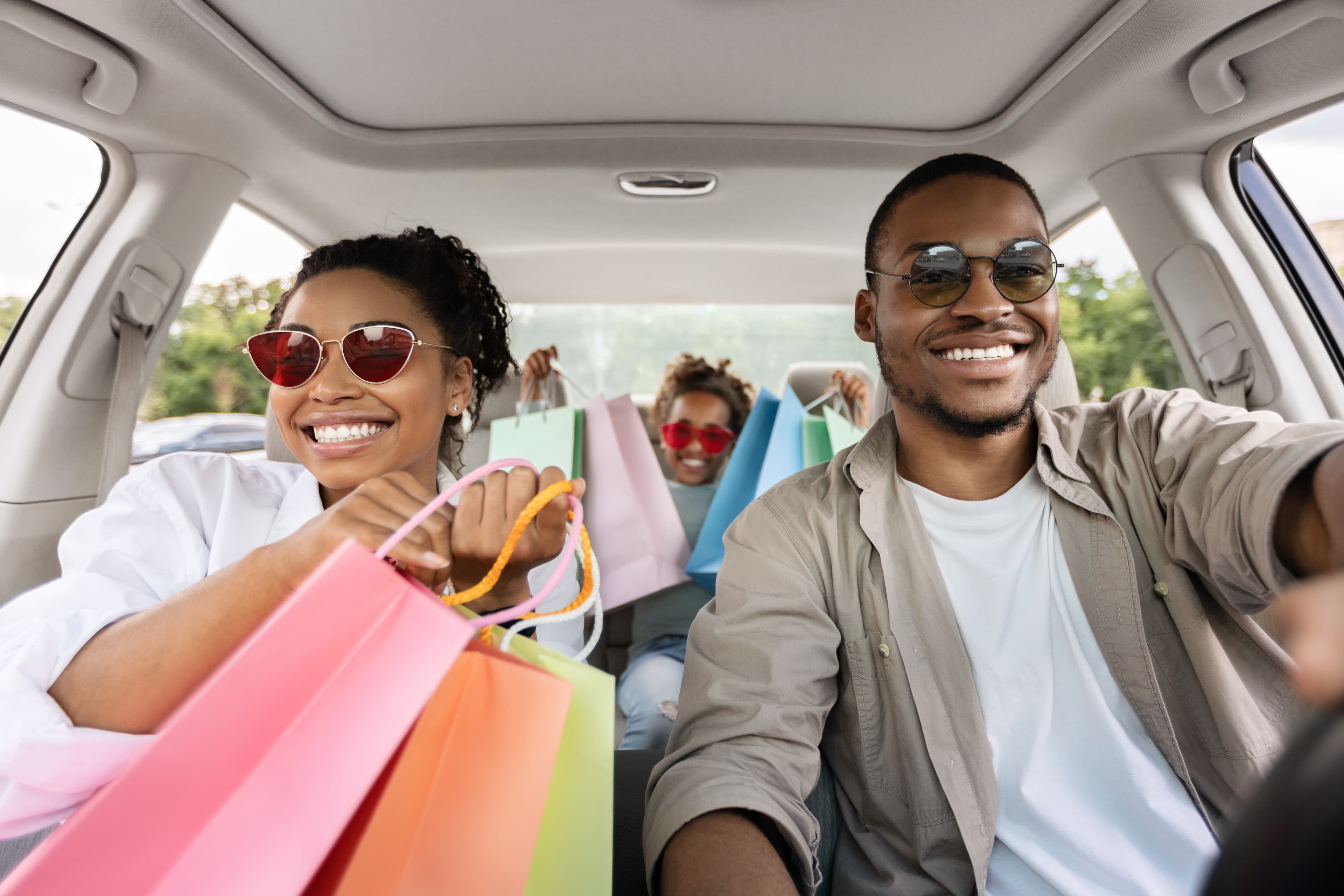 Happy  Parents And Daughter Riding Car Holding Colorful Shopper Bags After Shopping.