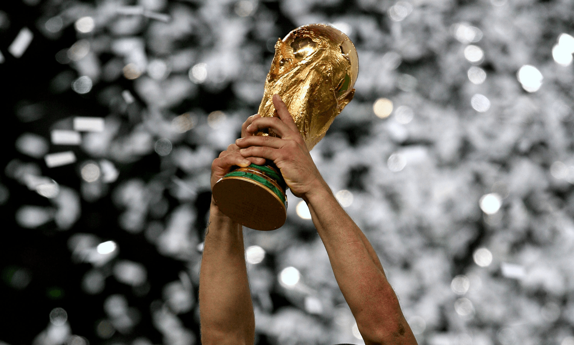 fifa world cup trophy held in the air with confetti in the background