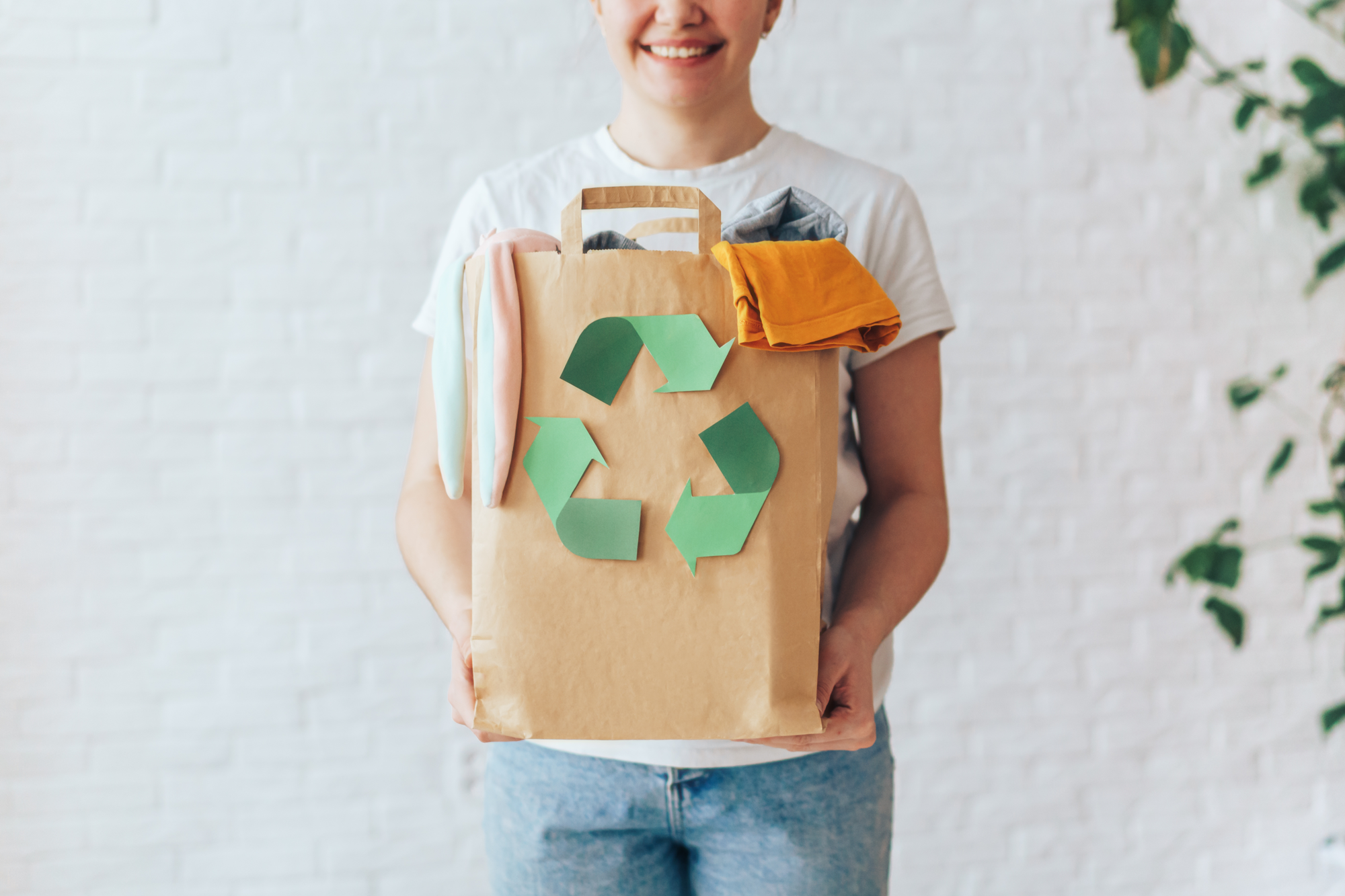 woman holding bag of recycled clothes on white background