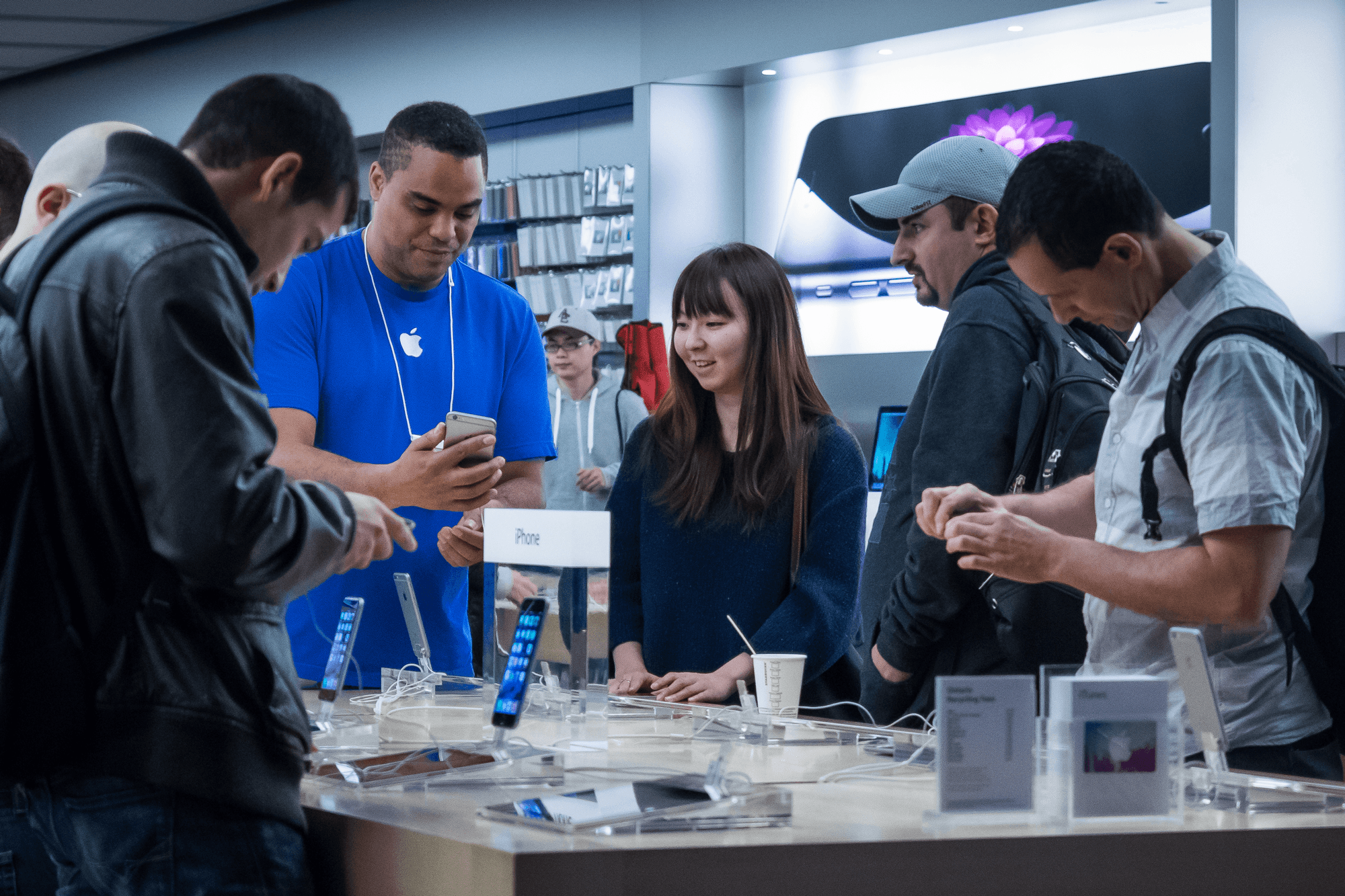 apple istore employee showing customers merchandise 