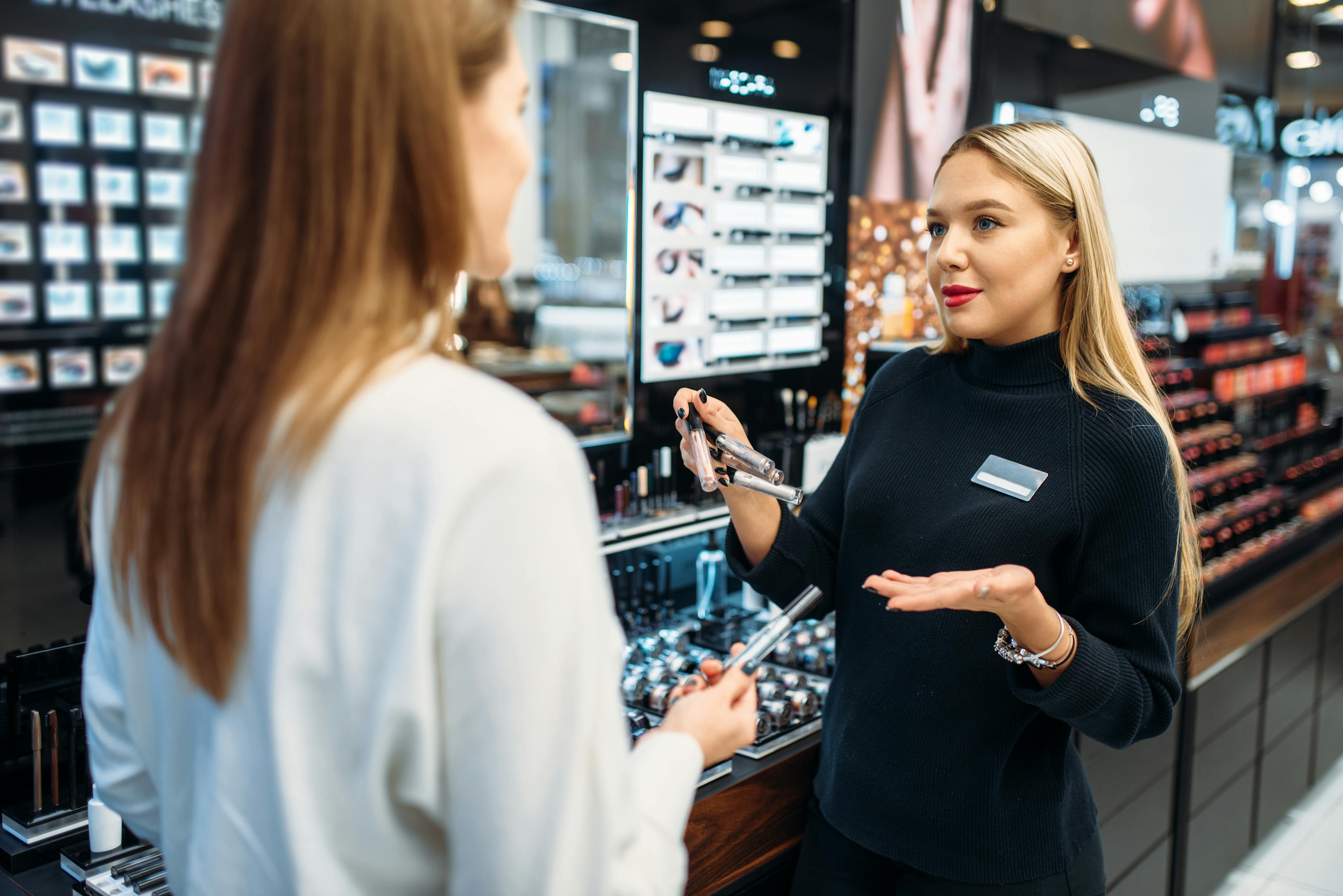 female sales associate helping shopper in cosmetic store