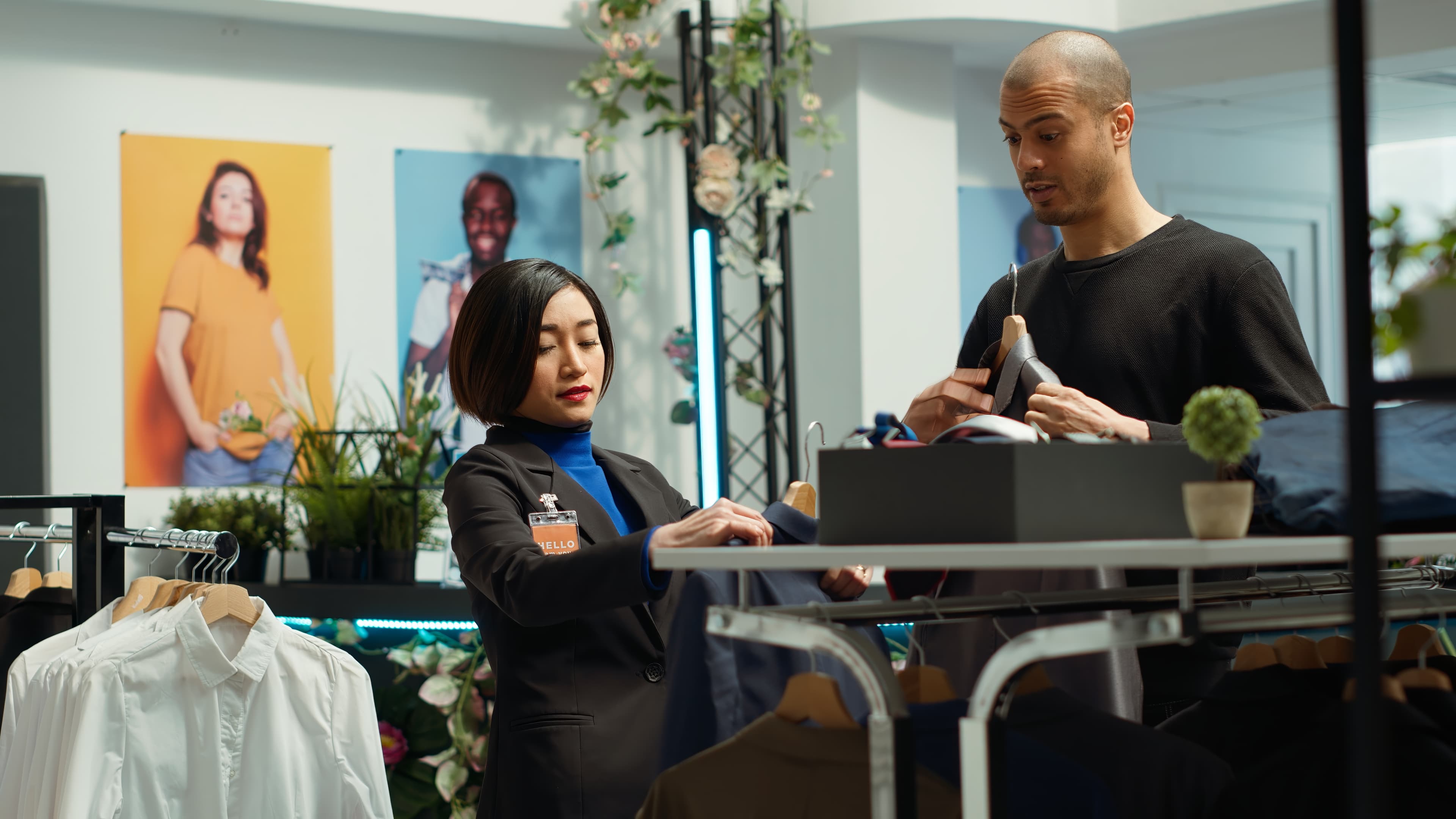 Store associate helps a young man client with style advice. Woman improves customer satisfaction.