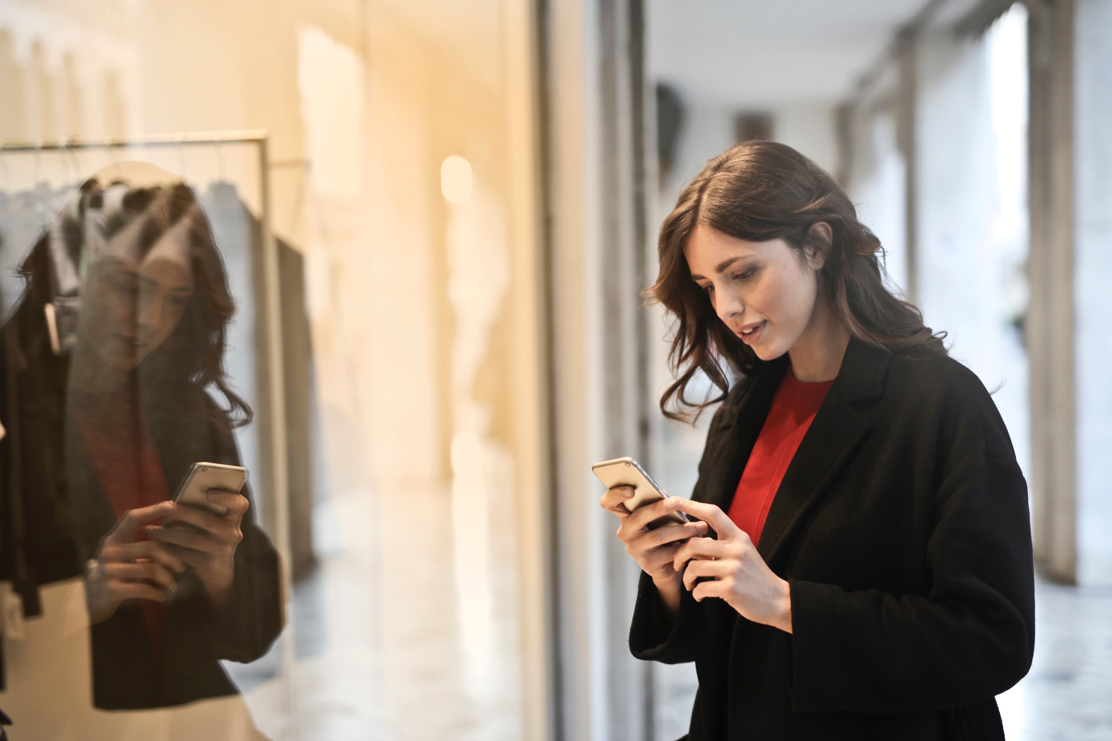 woman in shopping mall looking at phone in her hands 