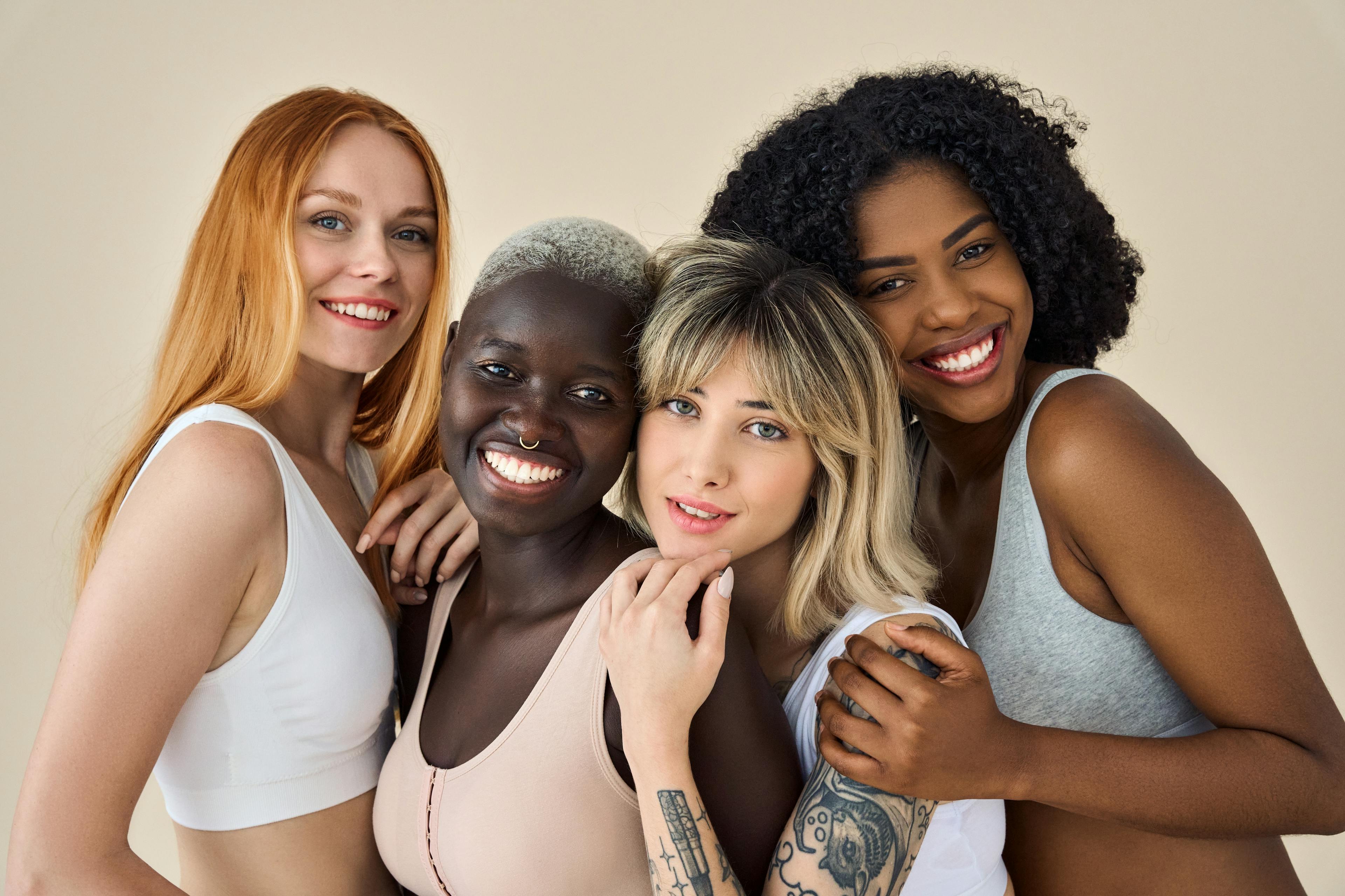 diverse group of four women posing in front of a beige background