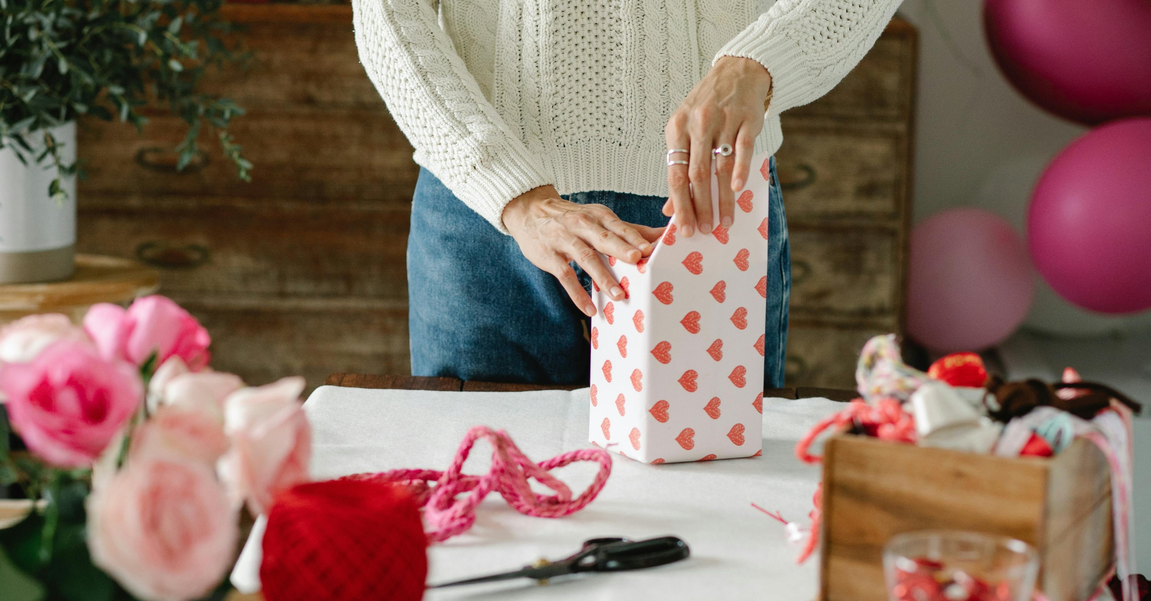woman wrapping valentines gift on white table