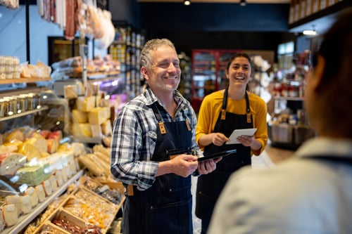 Happy business owner talking to some employees at a supermarket and smiling 