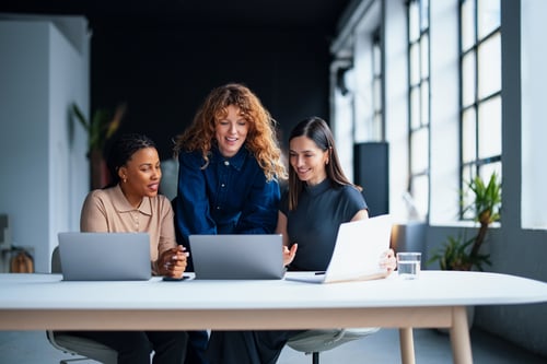 A team of women discussing at a workplace, discussing RetailNext's Pulse AI