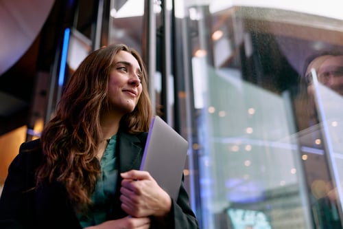 retail executive with laptop looking hopeful in modern office building